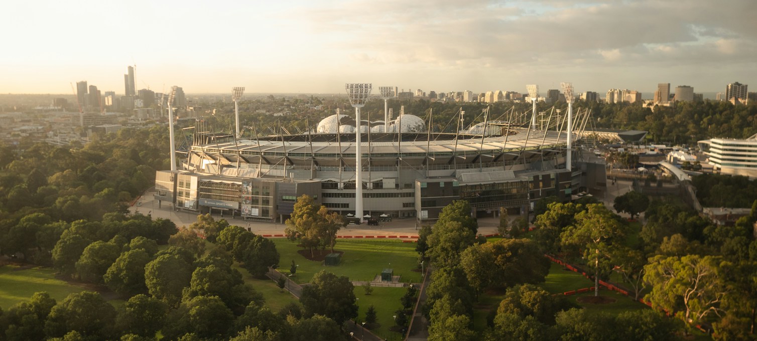 Aerial view of Melbourne Park with the Australian Open arenas and Melbourne's skyline in the background