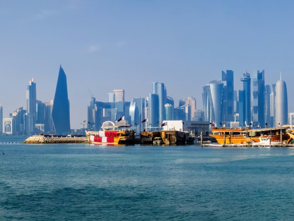 Qatar : A blurry photo of a city skyline in the middle of the ocean