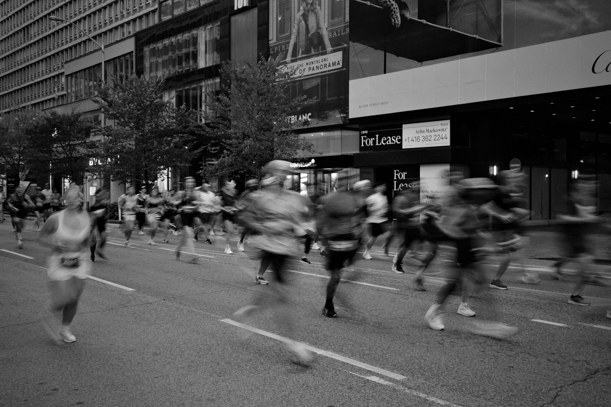 Corridori lanciati in gruppo lungo una strada cittadina durante una maratona