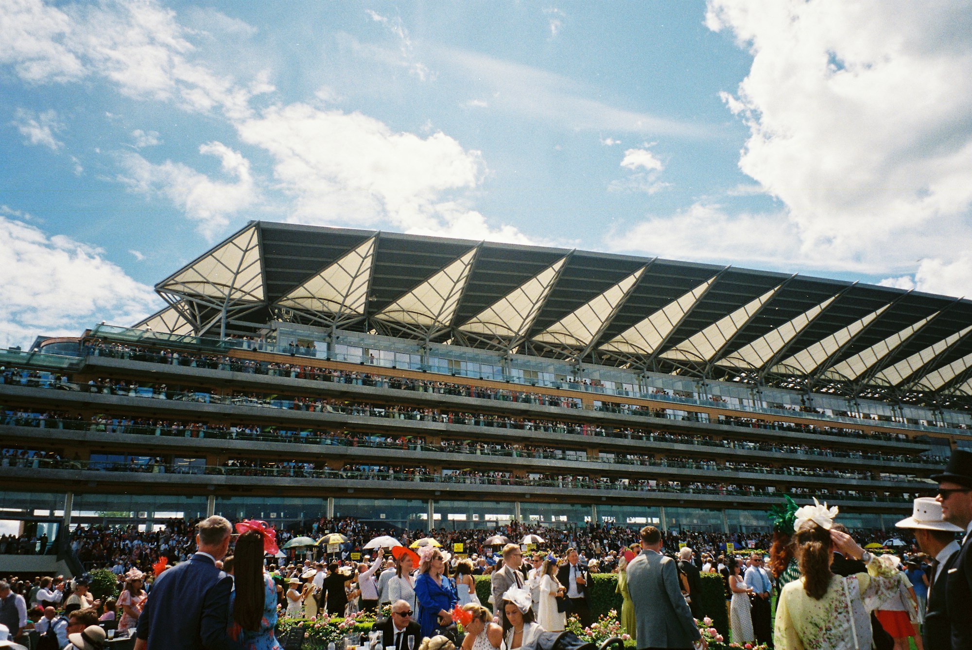 Elegantly dressed crowd in the stands of a racecourse