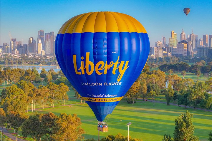 Hot air balloon flying over Melbourne's skyline at sunrise