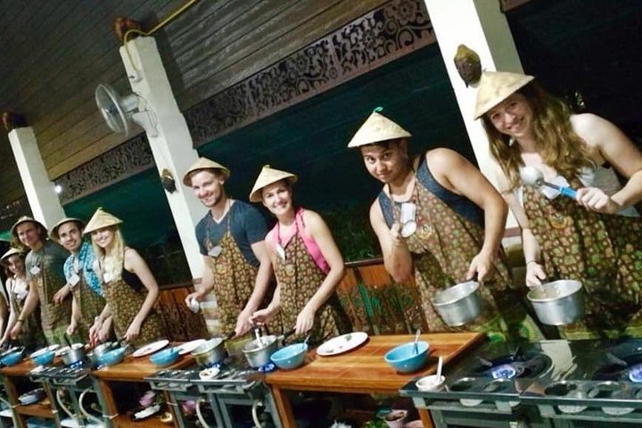Participants en tablier et chapeau pendant un cours de cuisine du soir à Chiang Mai