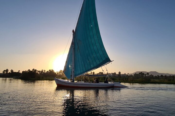 White-sailed felucca on the Nile in Luxor at sunset