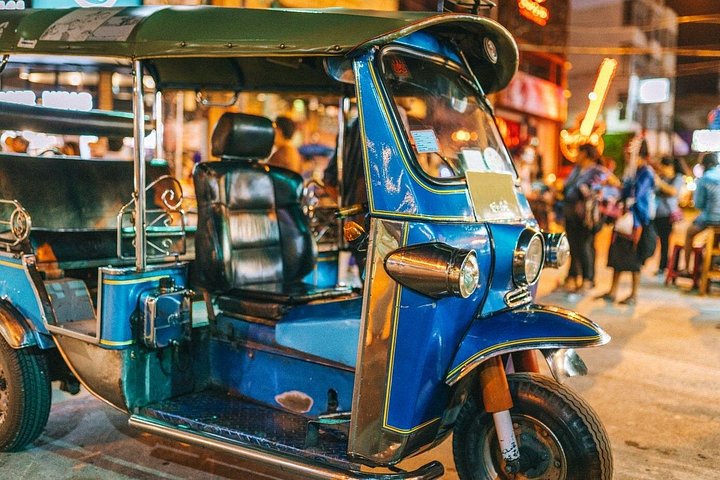 Tuk-tuk bleu garé dans une rue animée de Chiang Mai à la tombée de la nuit
