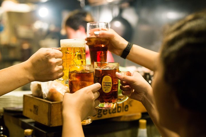 Belebte Izakaya-Gasse mit beleuchteten Lokalen in Shinjuku, Tokio, bei Nacht