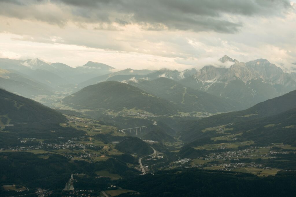 Vallée de montagne avec une route qui traverse le paysage sous un ciel nuageux