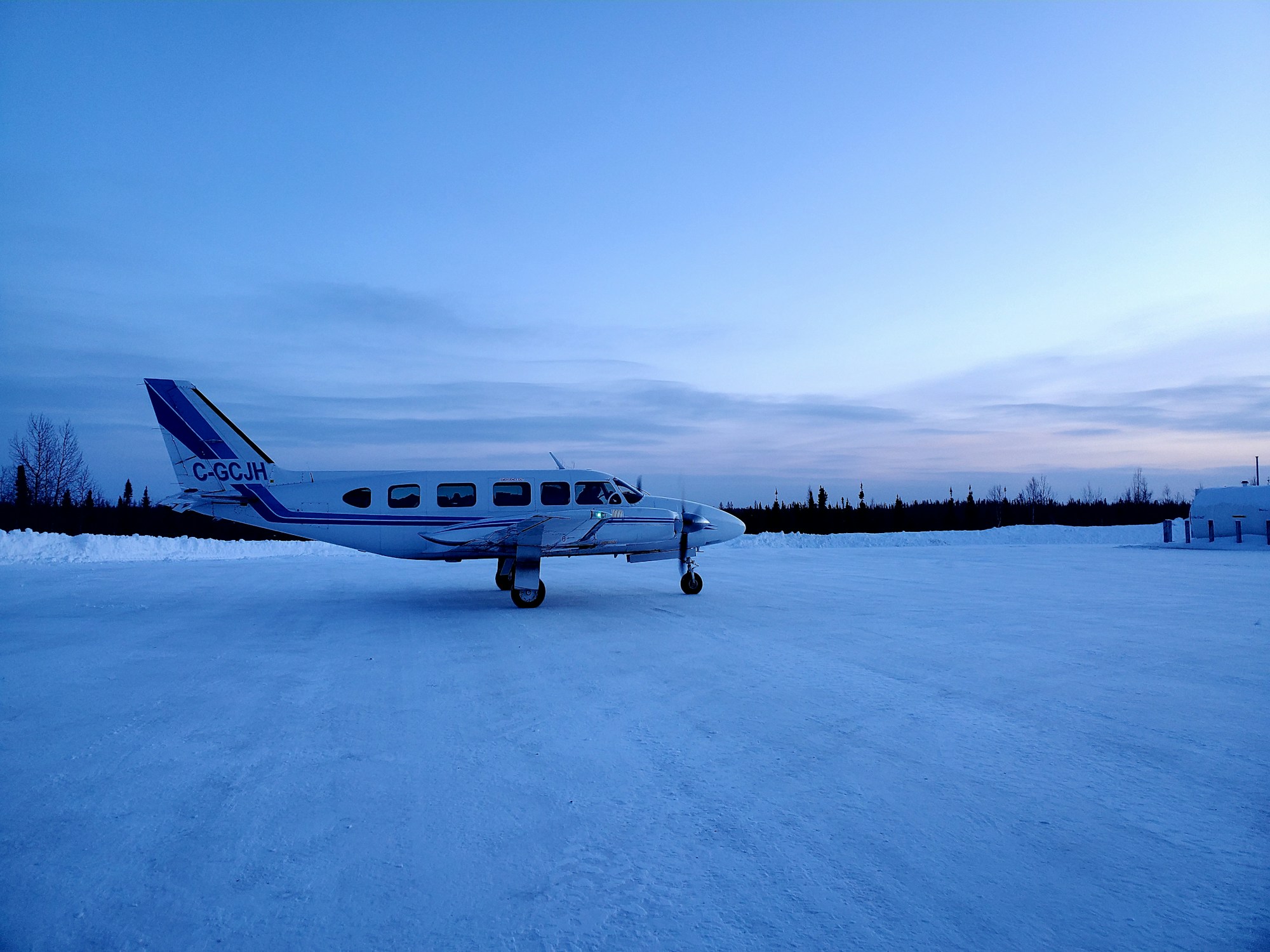 Small Canadian-registered plane on a snowy runway at dusk