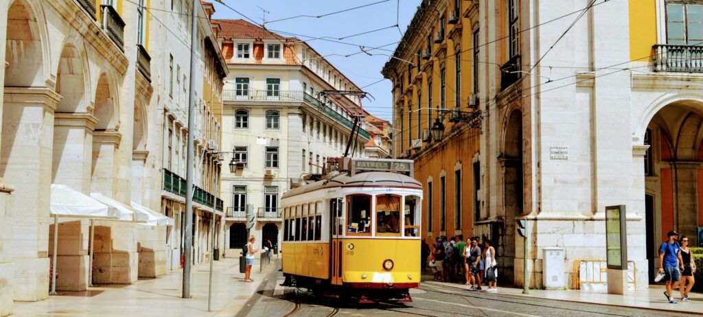 Yellow tram on a street lined with historic buildings in Lisbon
