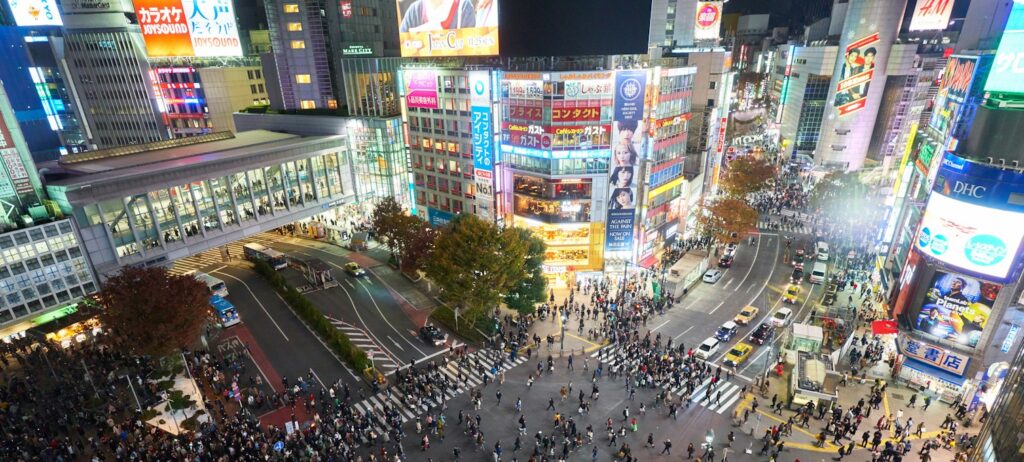 Pedestrians crossing a busy Tokyo street at night
