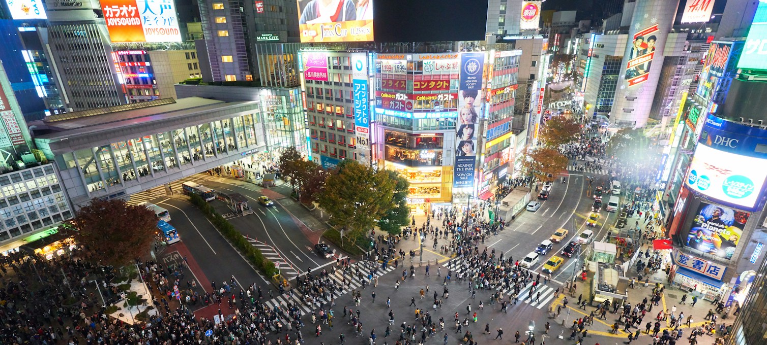 Pedestrians crossing a busy Tokyo street at night
