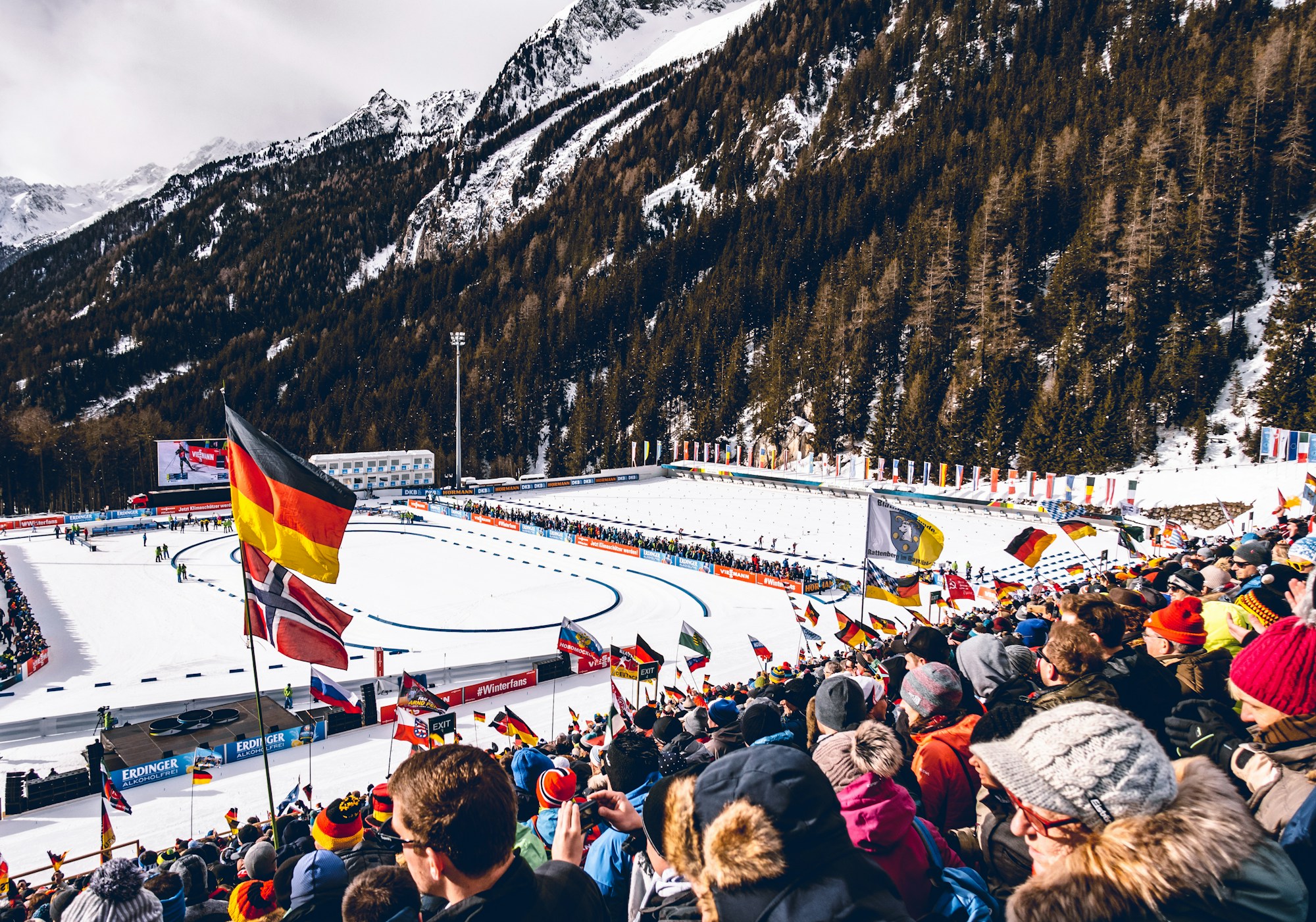 Spectateurs regroupés face à une piste enneigée lors d'une compétition de sports d'hiver