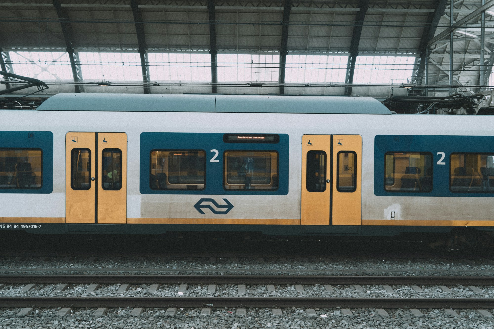 Bahnsteig eines niederländischen Bahnhofs mit einem haltenden Regionalzug