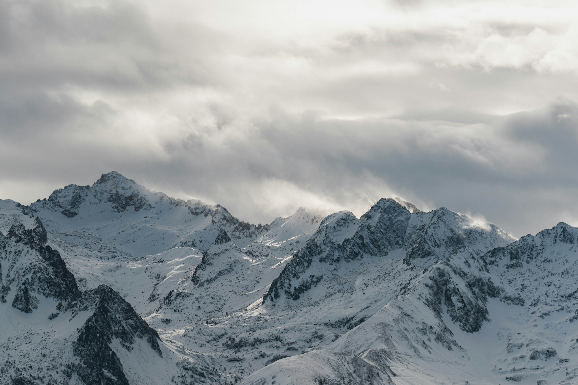 Gebirgskette, mit Schnee bedeckt, unter bewölktem Himmel