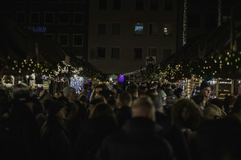Marché de Noël de nuit, étals illuminés et foule sur une place