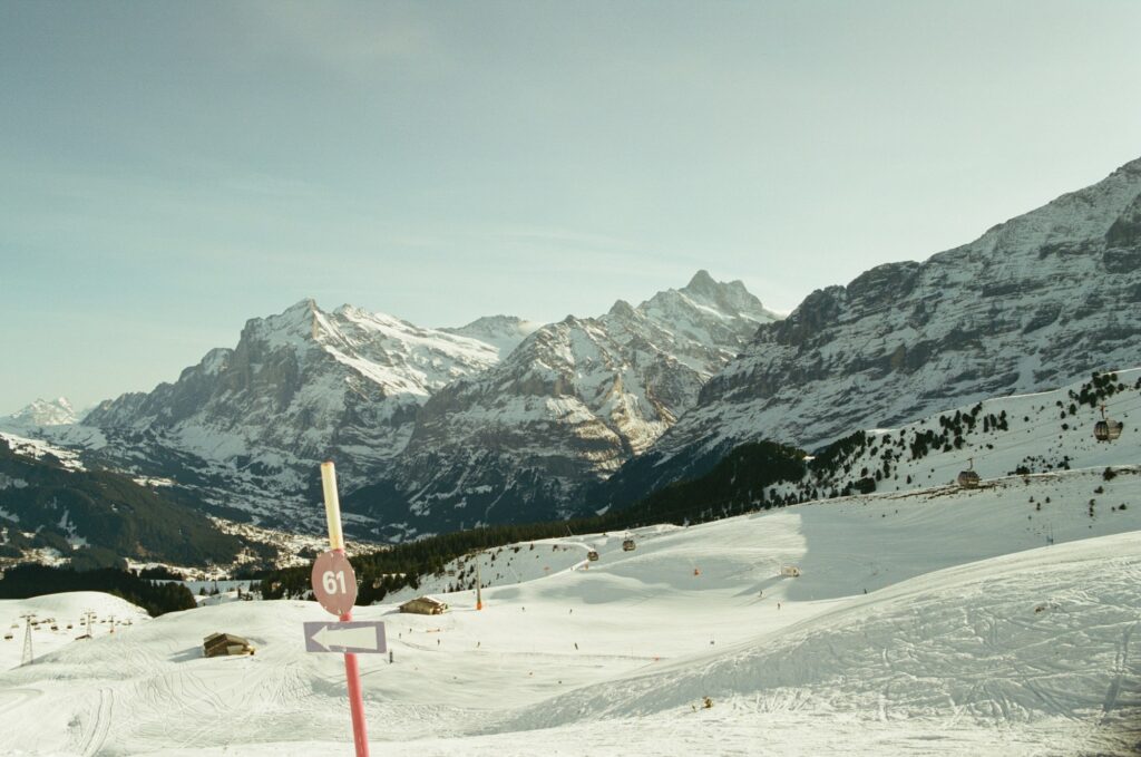 Piste de ski enneigée sous les sommets alpins suisses, avec un panneau de piste au premier plan