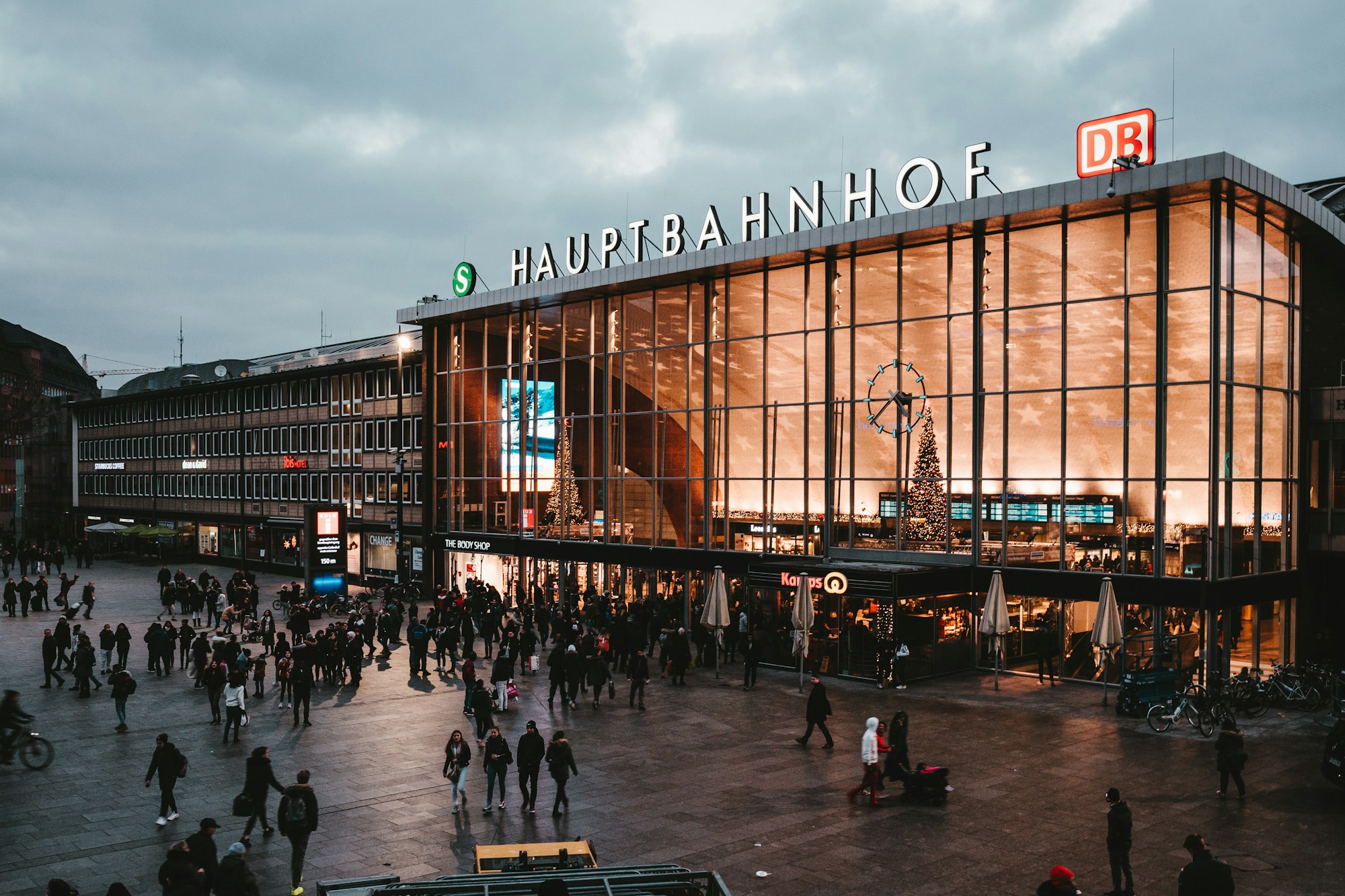 Vorplatz des Kölner Hauptbahnhofs mit Reisenden am Abend