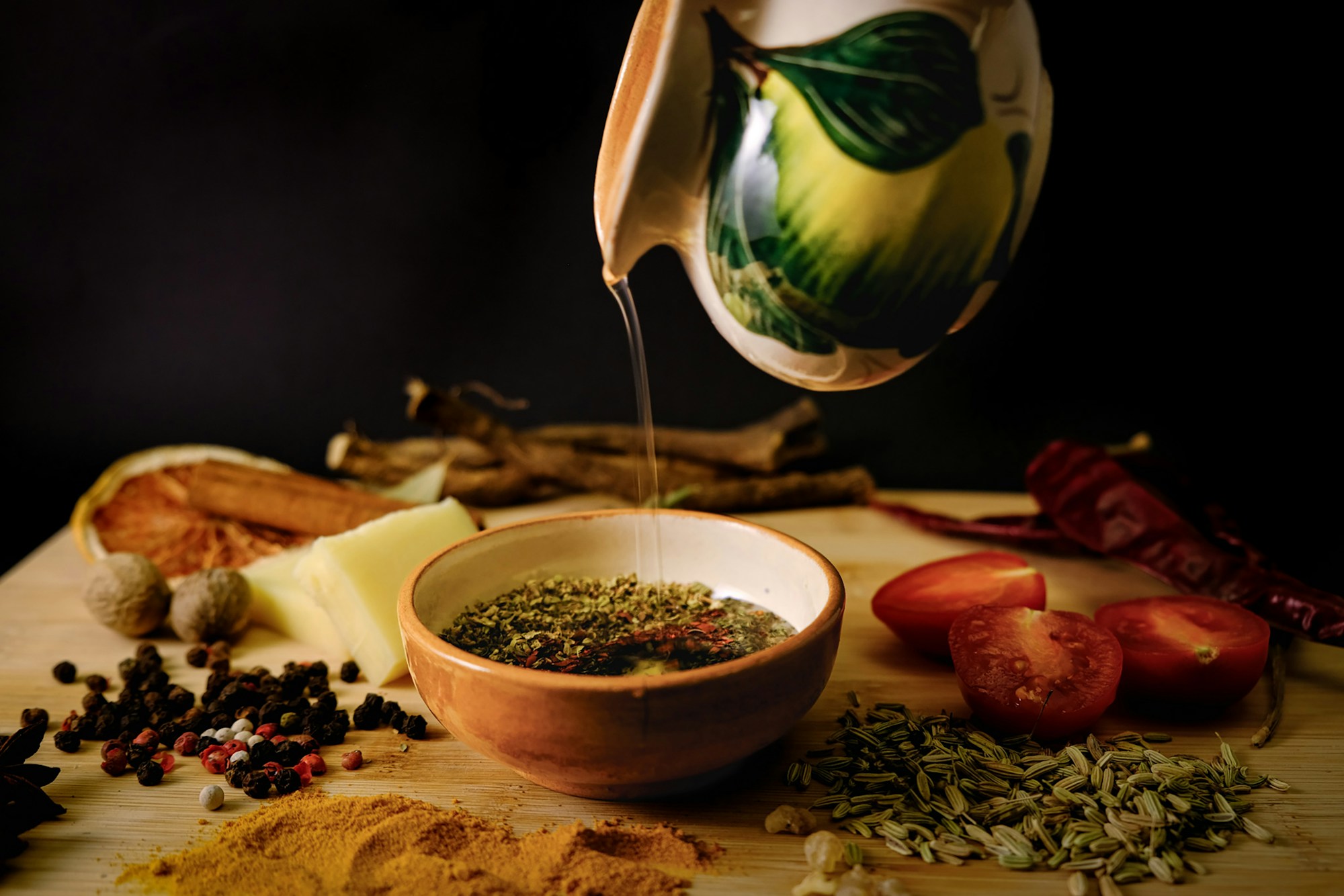 Olive oil poured into a bowl with fresh herbs