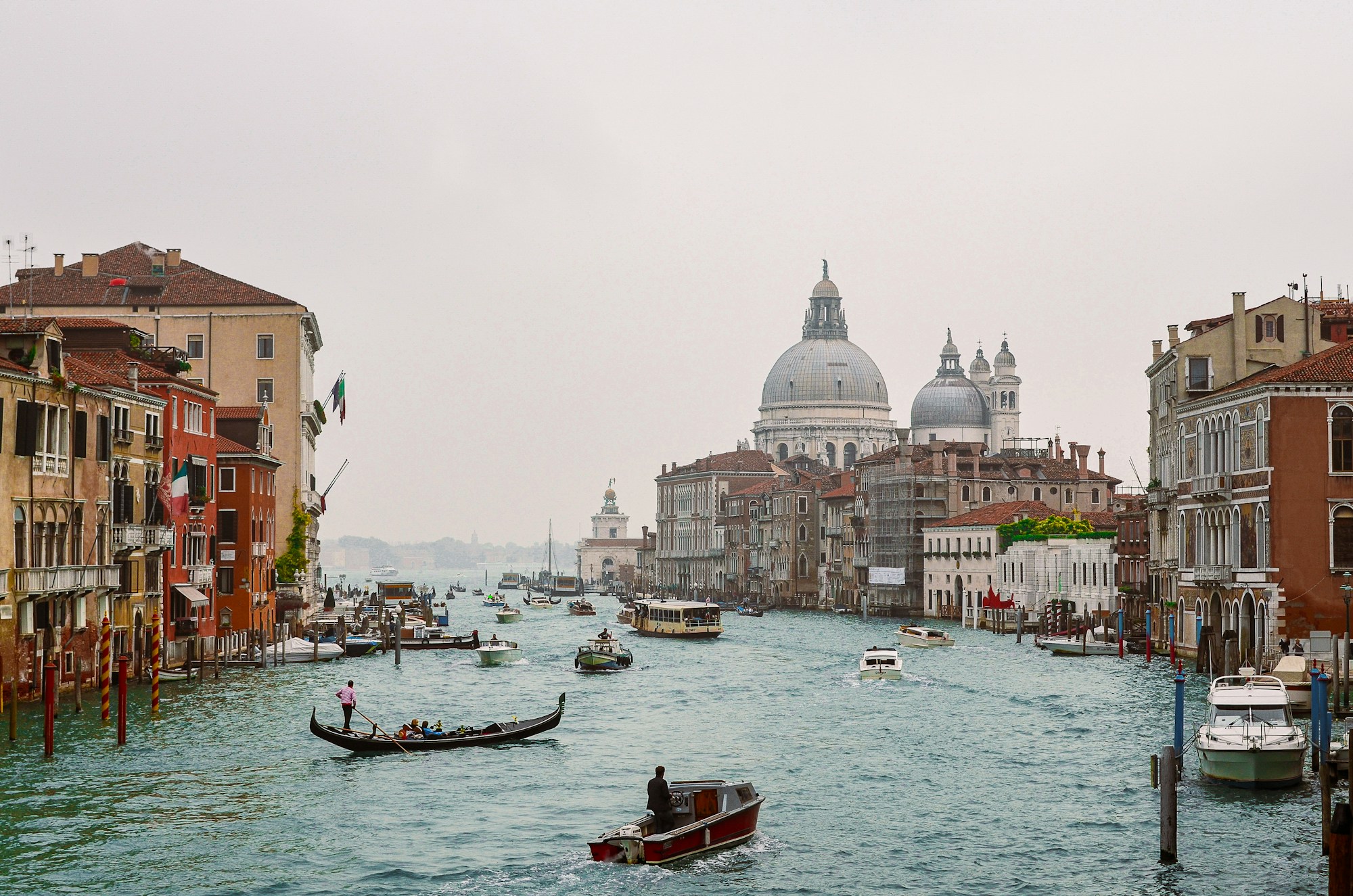 Grand Canal in Venice on a grey day, with a gondola and the Salute basilica in the background