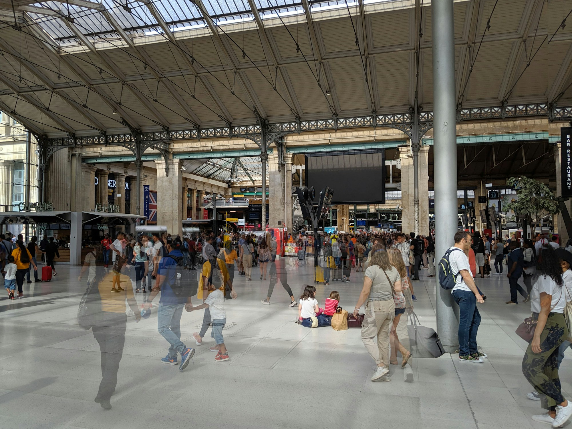 Reisende mit Koffern in einem großen Pariser Bahnhof
