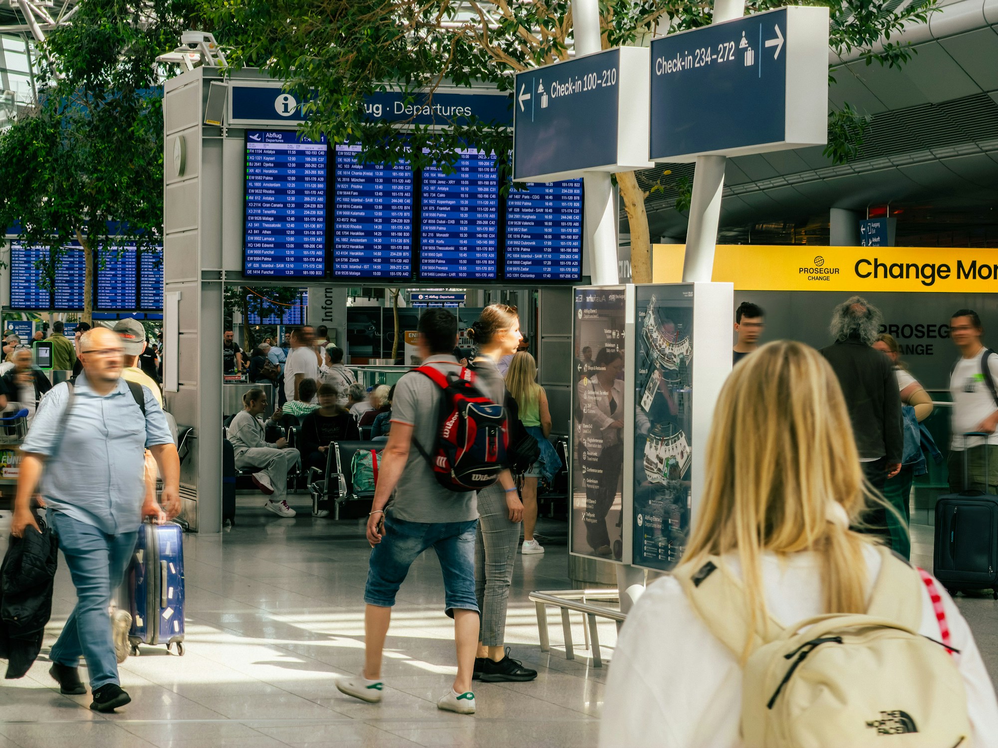 Reisende in der Abflughalle eines Flughafens vor der Anzeigetafel