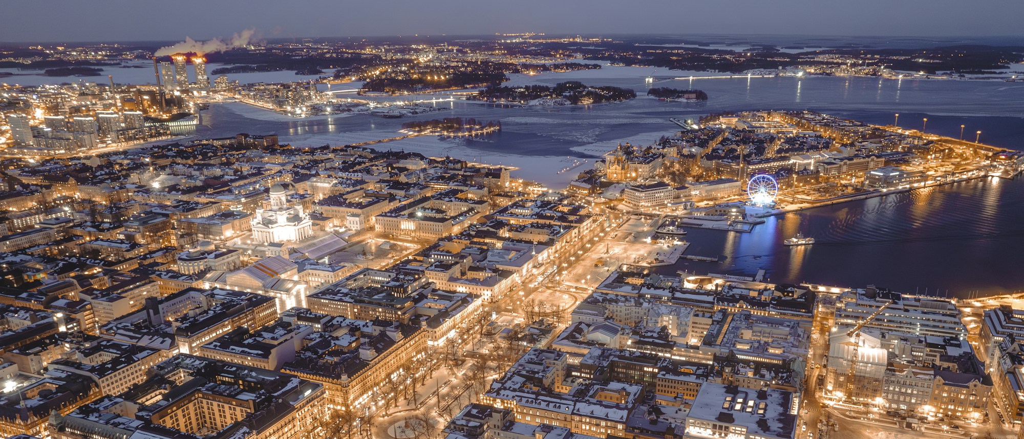 Night aerial view of Helsinki in winter, snow-covered rooftops and lit buildings