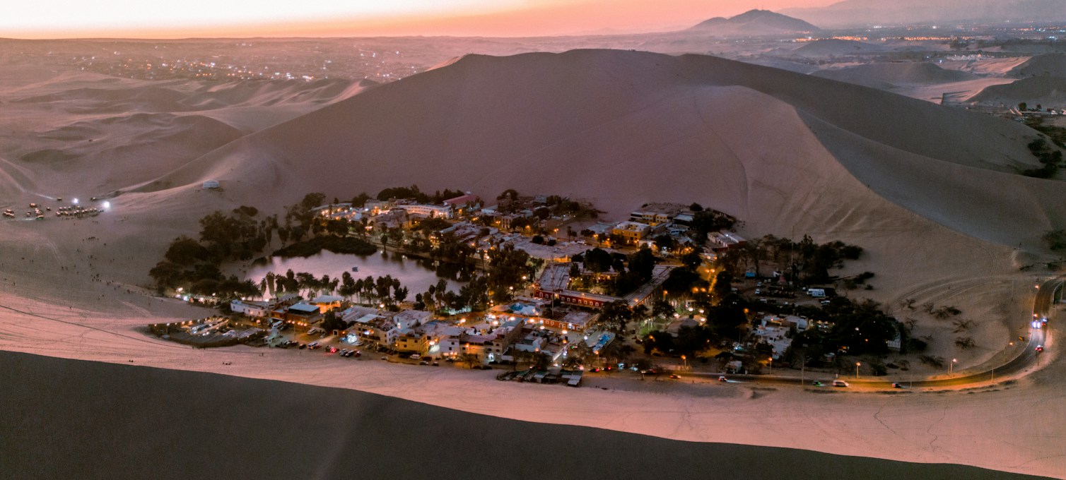 Huacachina oasis surrounded by sand dunes at sunset