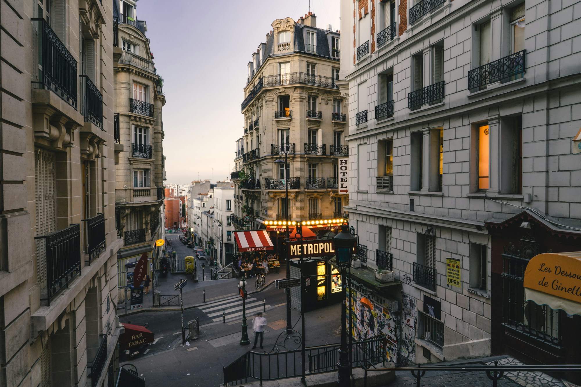 Rue parisienne au crépuscule, façades haussmanniennes et enseignes lumineuses