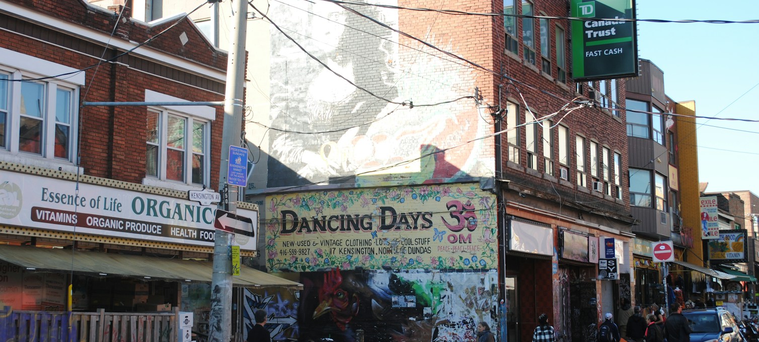 Belebte, bunte Straße in Kensington Market in Toronto mit bemalten Fassaden und Verkaufsständen im Freien