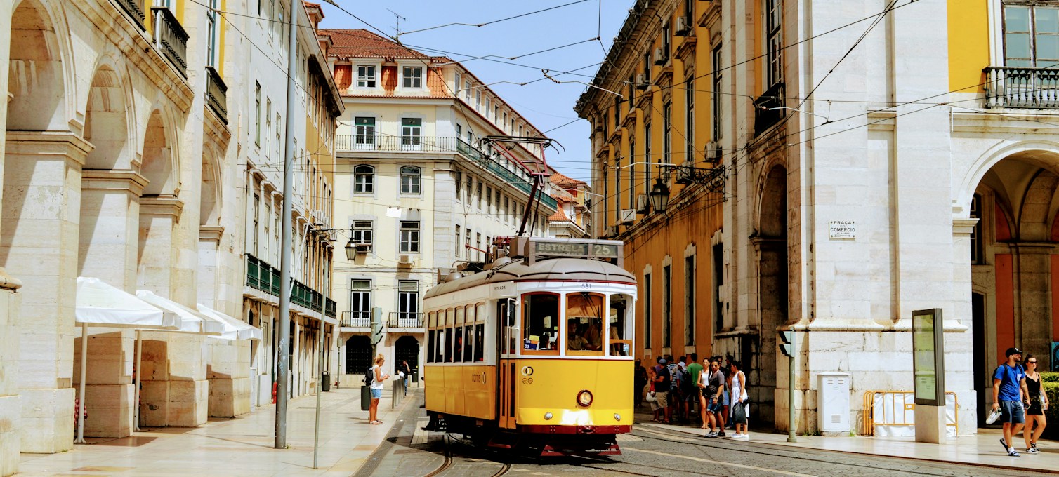 Yellow tram climbing a steep street in Lisbon