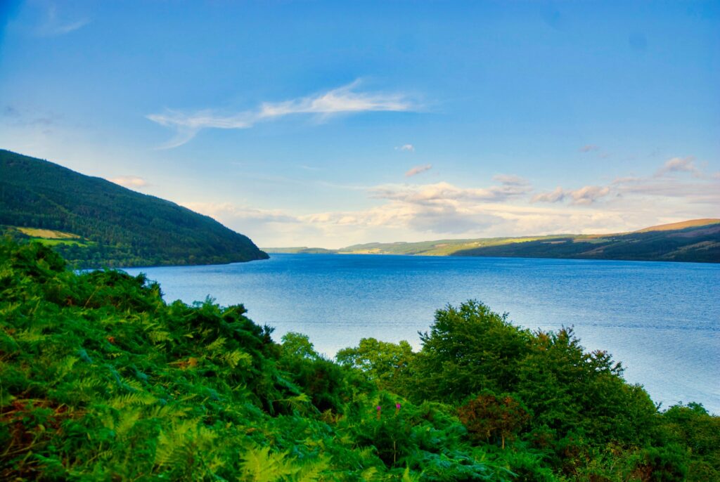 Loch Ness with green hills and a blue sky, Scottish Highlands