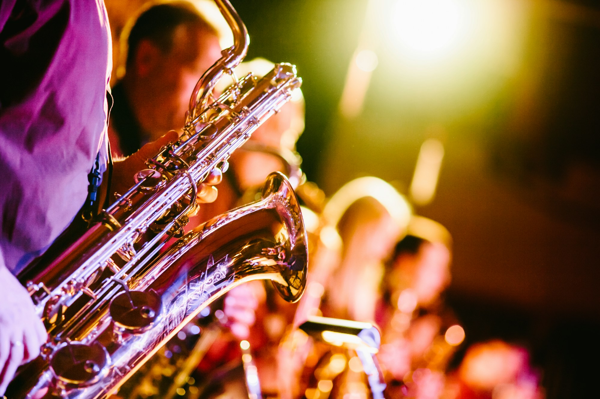 Saxophone joué sur scène lors d'un concert de jazz, lumière violette et dorée