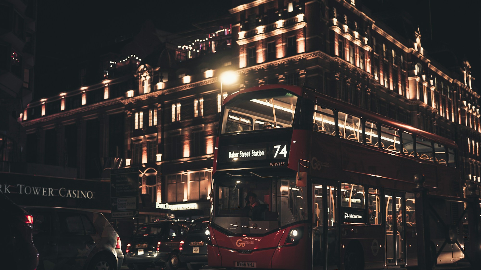 Bus rouge à impériale circulant la nuit dans une rue de Londres