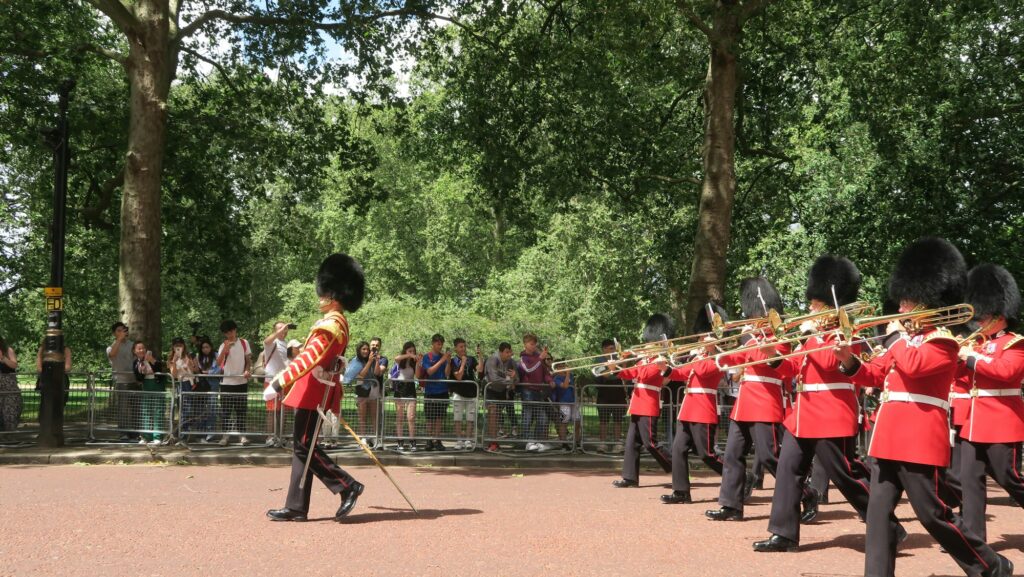 Fanfare militaire de la Garde défilant à Londres, avec des spectateurs derrière les barrières