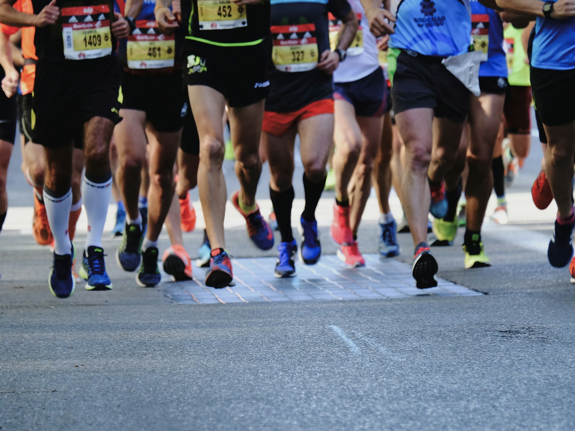 Runners on an urban road at sunrise, seen from behind