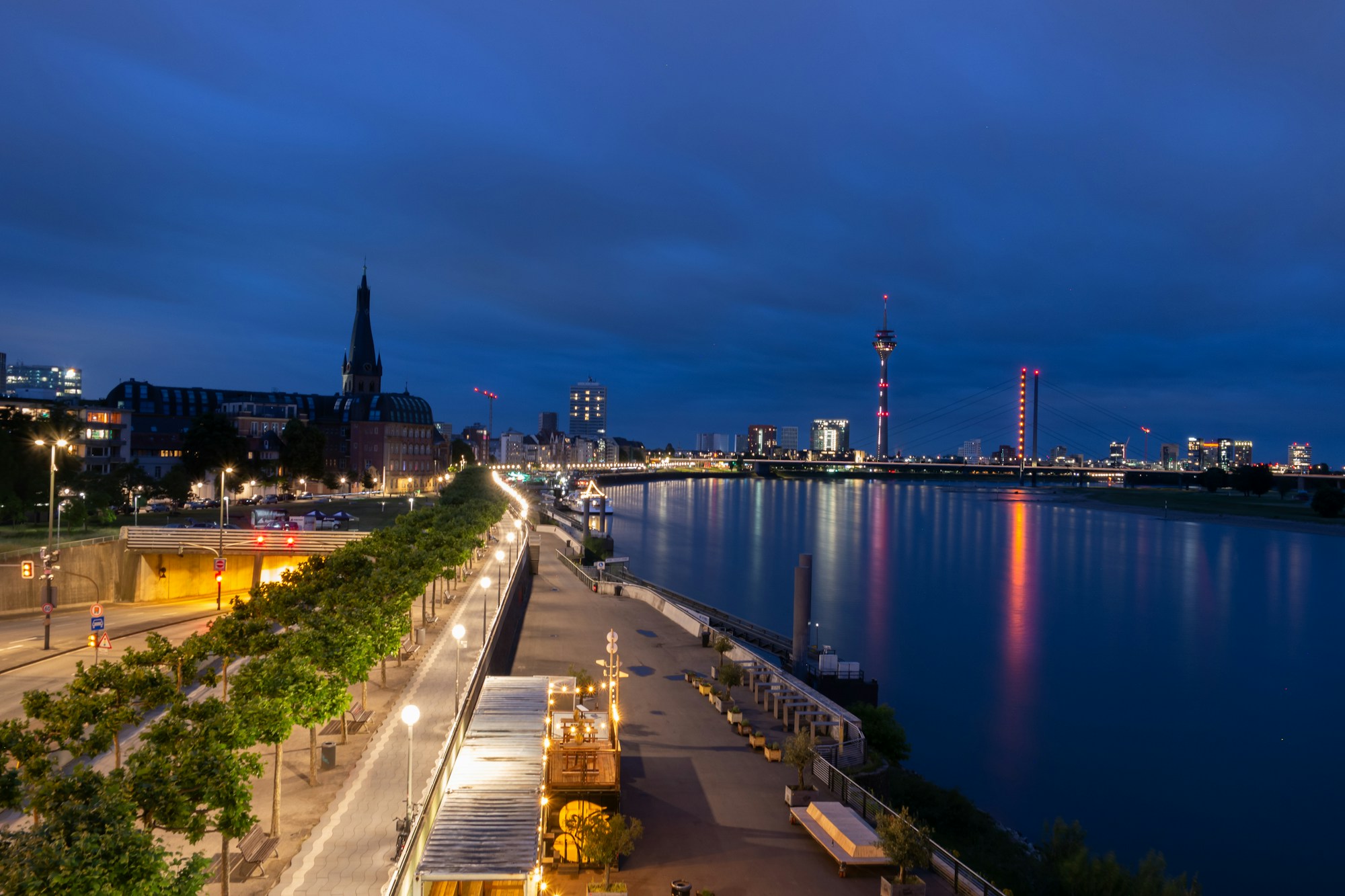The Rhine in Düsseldorf at night, a lit promenade and bridges in the distance