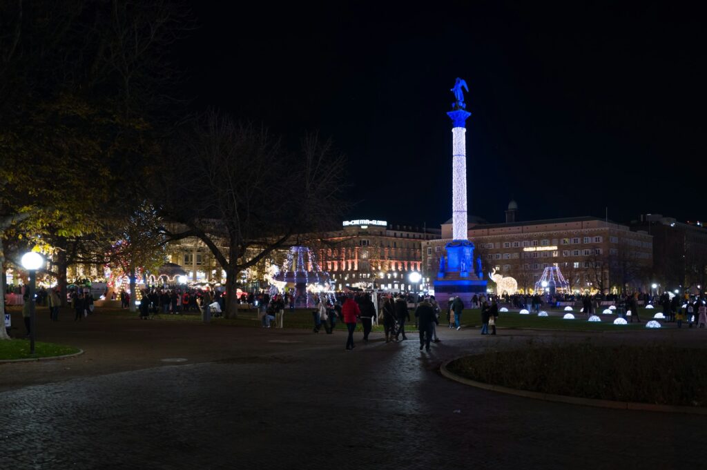 Vue nocturne de la place Schlossplatz à Stuttgart pendant le marché de Noël, avec une colonne illuminée