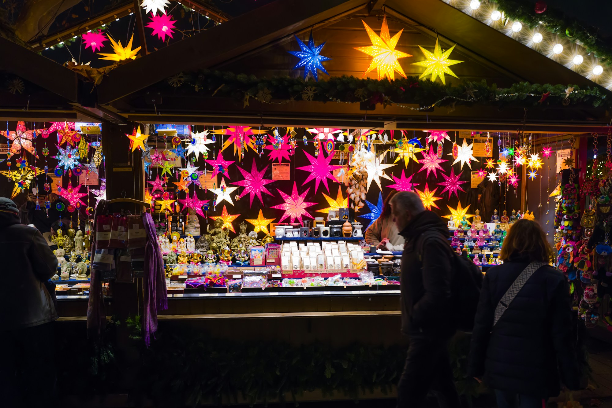 Puesto del mercado de Navidad iluminado de noche en Stuttgart, decorado con estrellas luminosas de colores