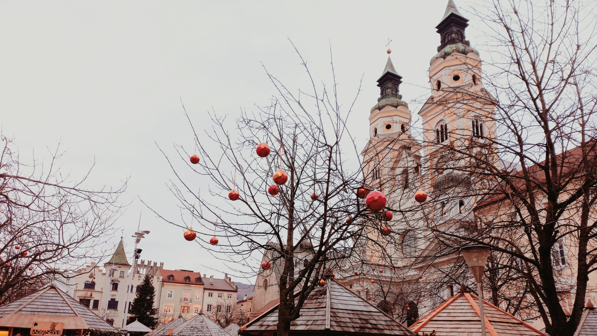 Rote Kugeln in den Bäumen vor dem Dom von Brixen während des Weihnachtsmarkts