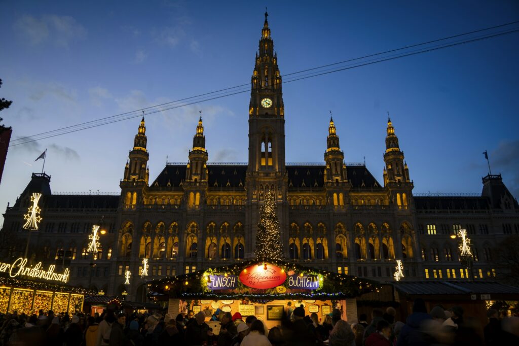 Stands illuminés du marché de Noël du Rathausplatz, devant l'Hôtel de Ville de Vienne, au crépuscule