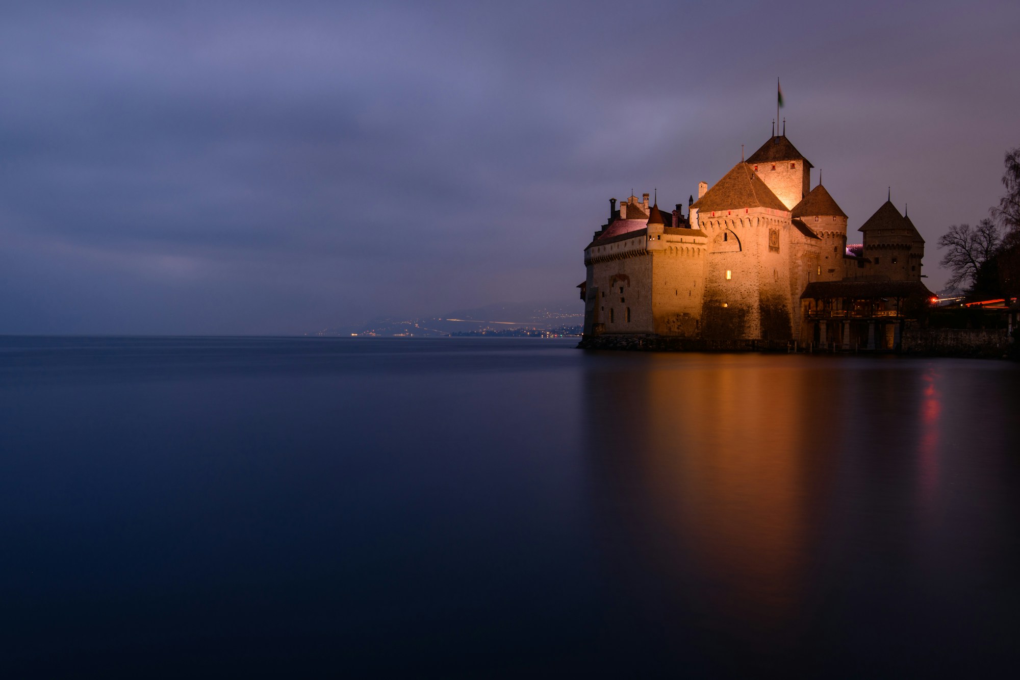 Castillo de Chillon a la hora azul, con las luces de Montreux a orillas del Léman