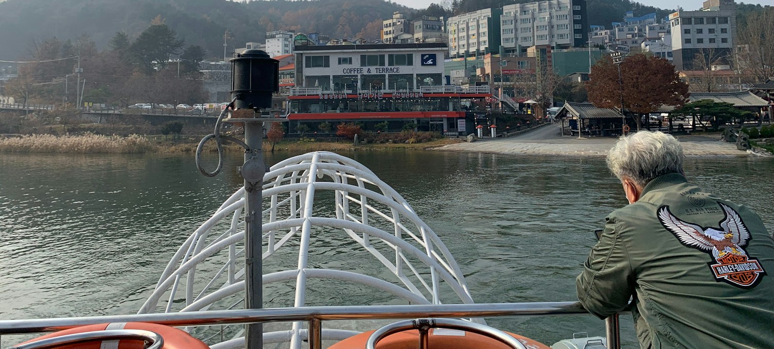 A ferry on the river at Gapyeong with autumn trees on the shore, the way to Nami Island