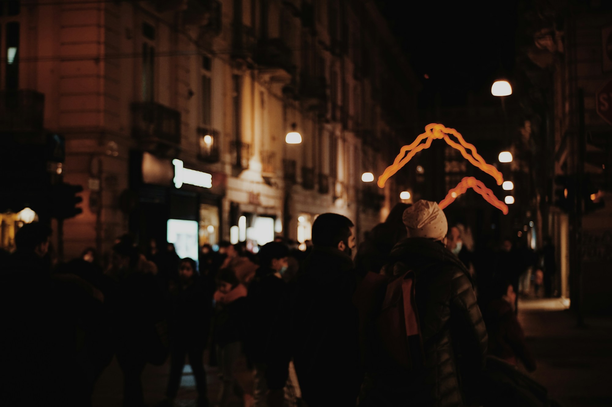 Belebte Straße im Zentrum von Turin bei Nacht, mit Passanten und Stadtlicht