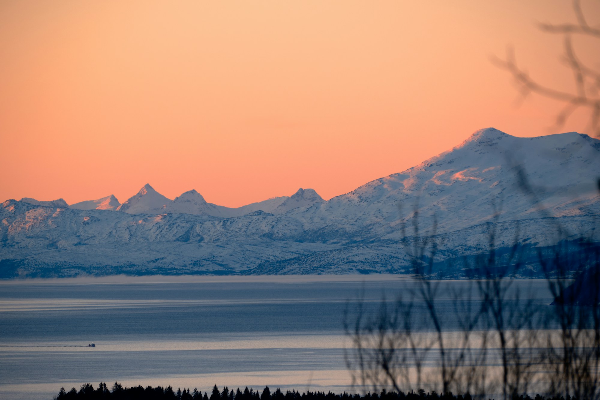Ruhige See in einem arktischen Fjord am Fuß verschneiter Berge, Norwegen
