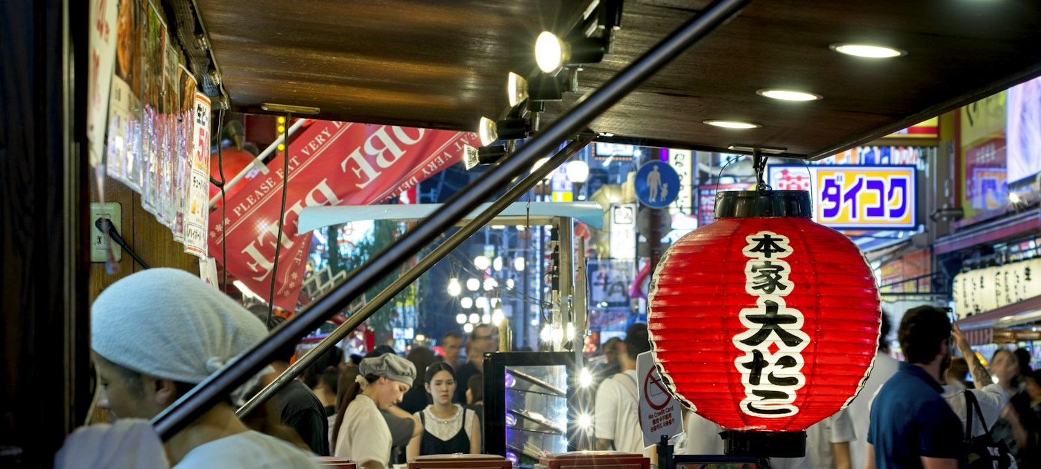 Beleuchteter Street-Food-Stand in einer Straße von Osaka am Abend