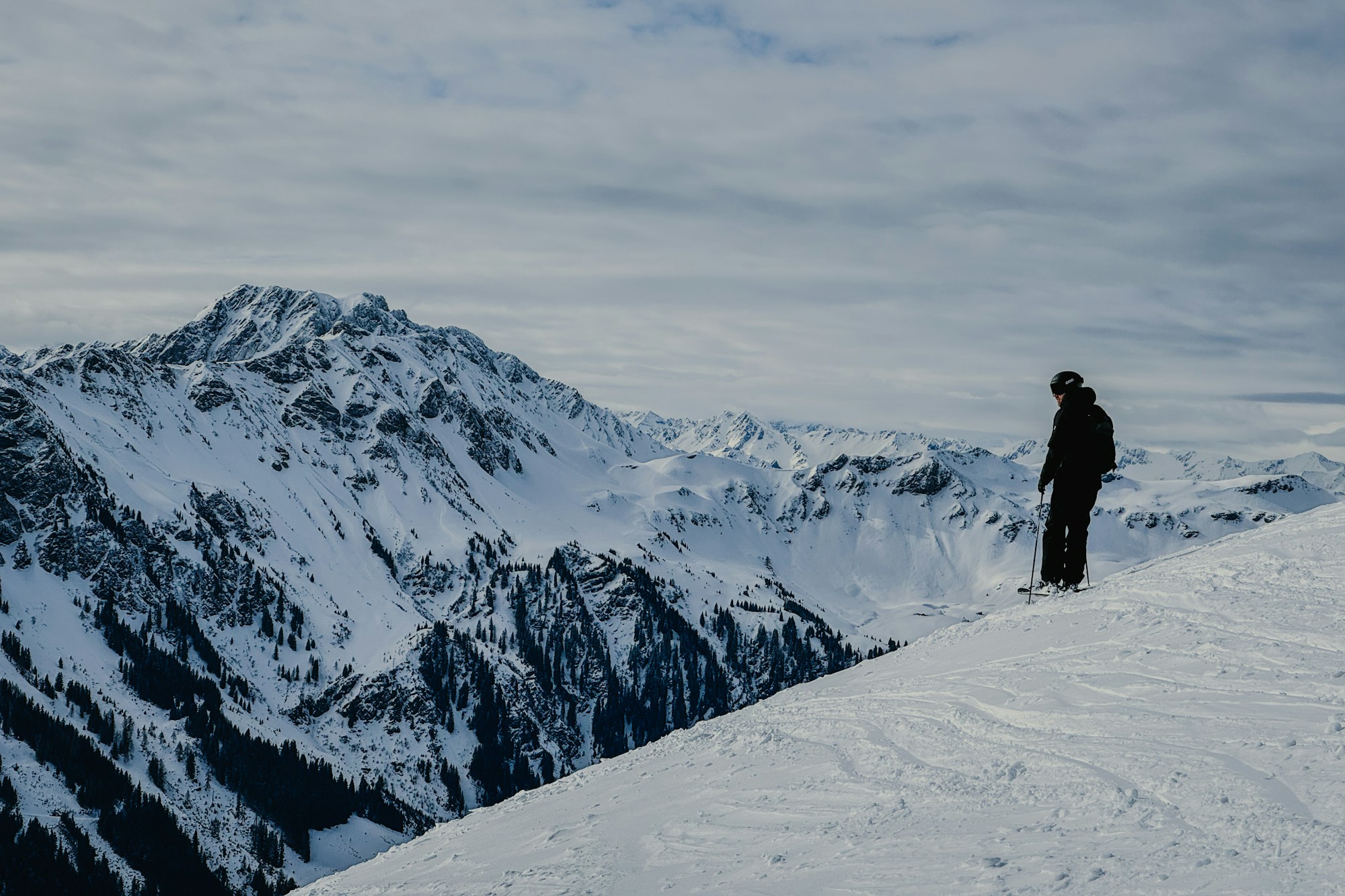 Skier on a snowy piste facing the peaks of Saalbach Hinterglemm