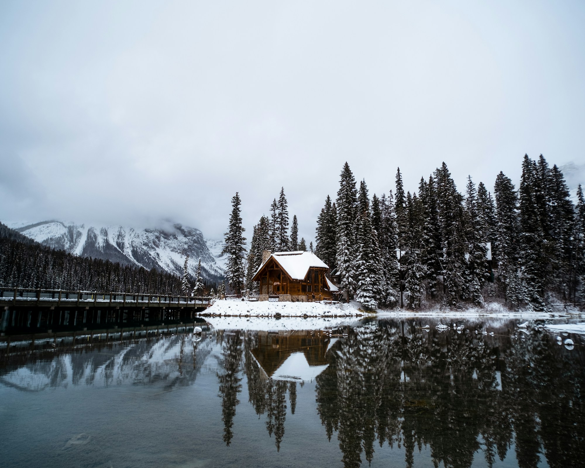 Chalet en bois au bord d'un lac enneigé des Rocheuses canadiennes