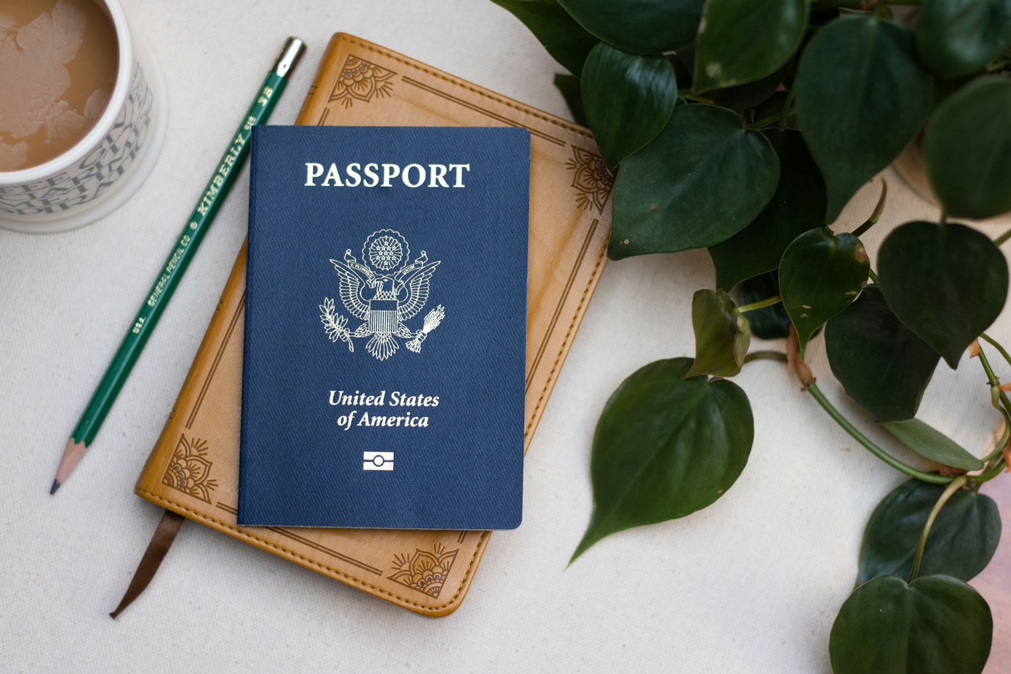 Passport, pencil and notebook on a table, next to a cup of coffee
