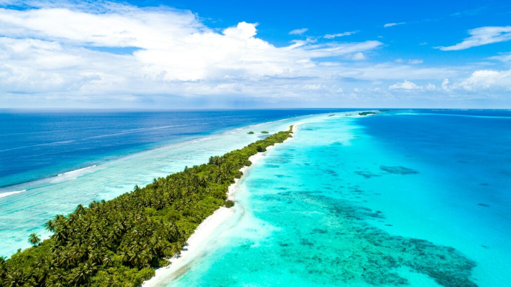 Vue aérienne d'une île bordée de sable blanc et d'un lagon turquoise aux Maldives