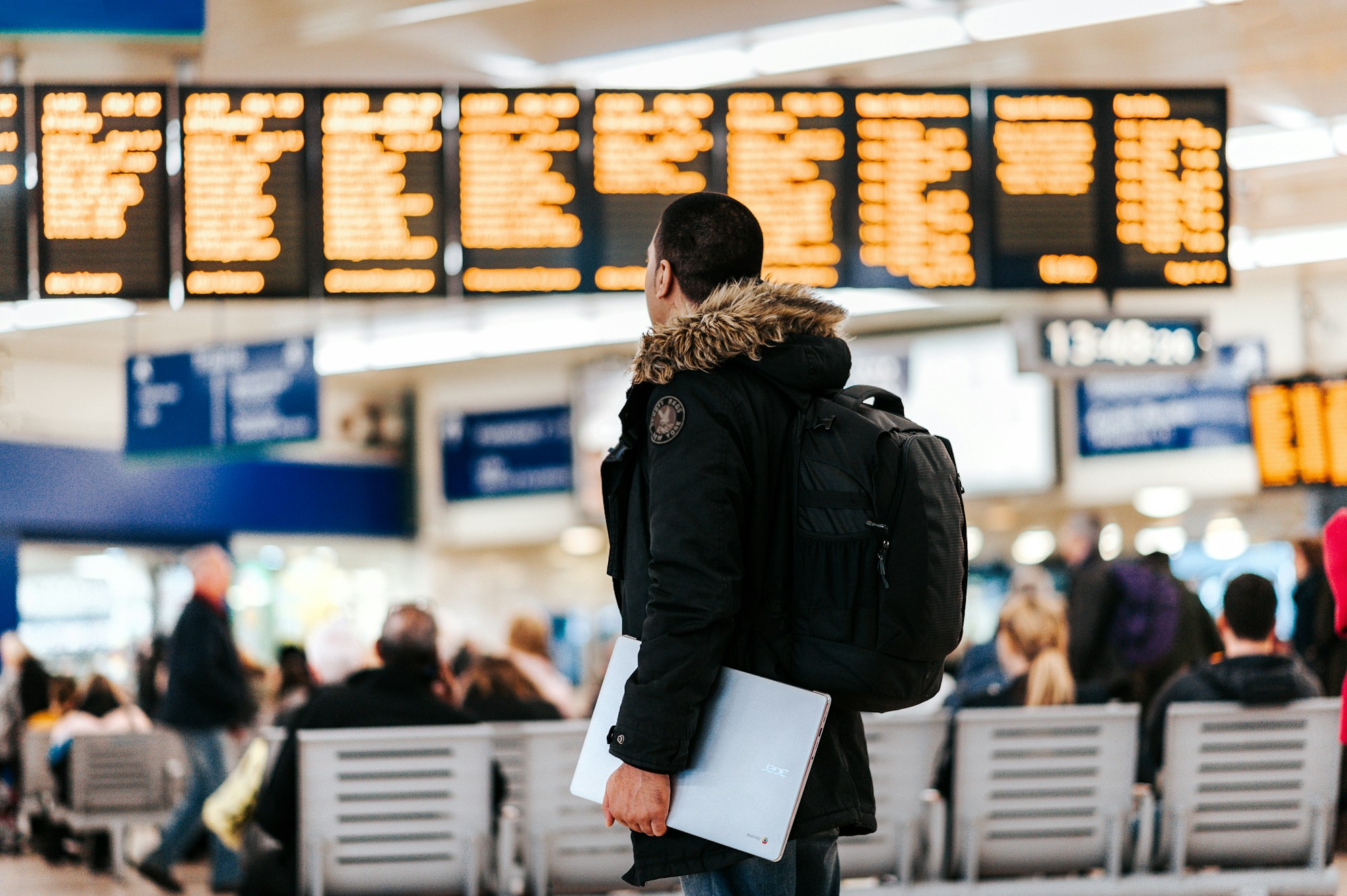 Traveller in front of an airport departures board, backpack on one shoulder