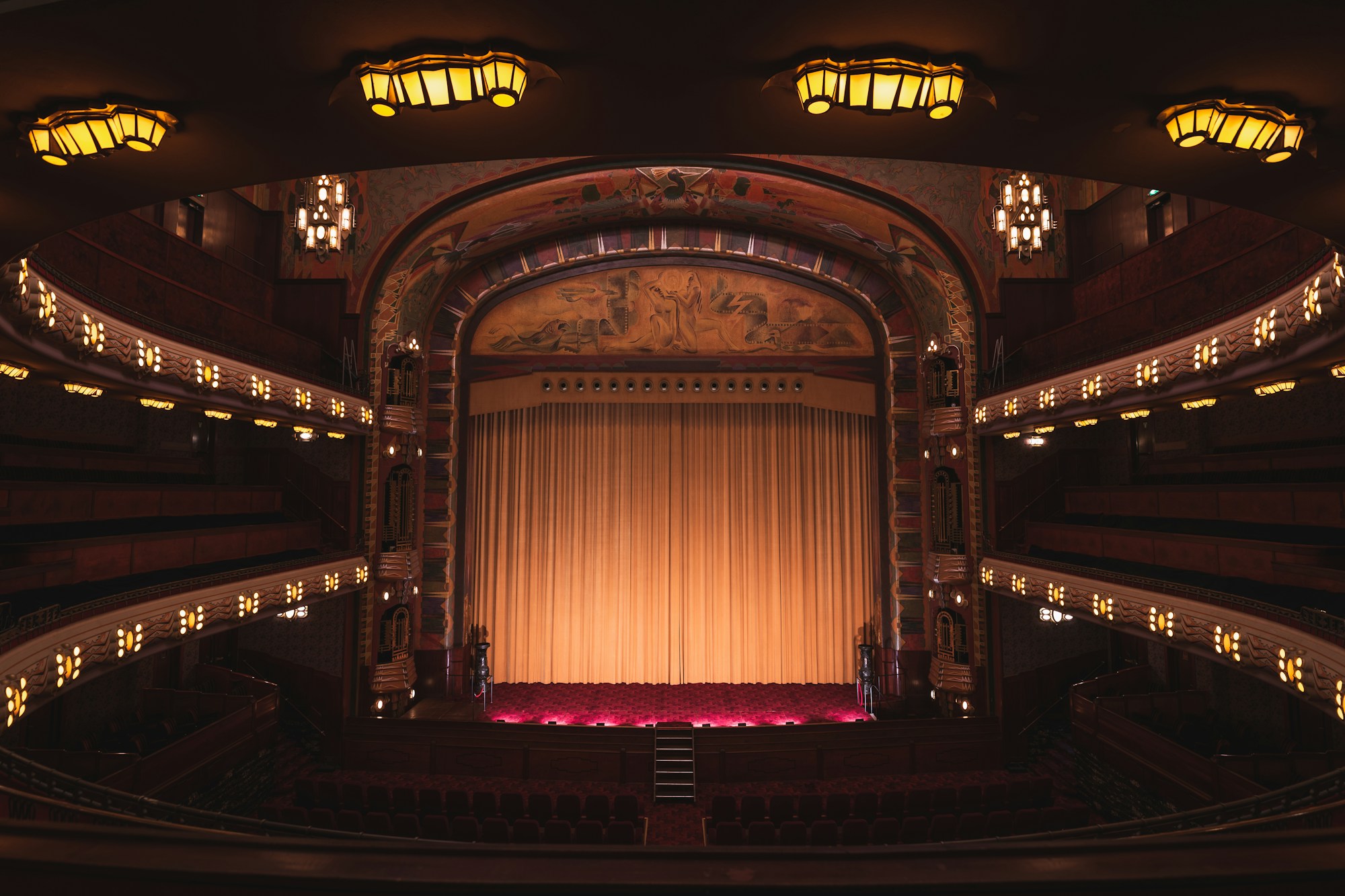 Bühne eines Theaters am Abend, helle Vorhänge und warmes Licht